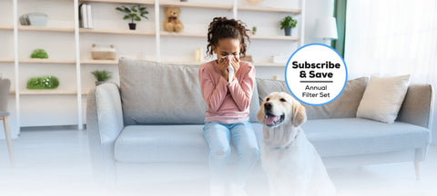 Young girl sneezing on the couch with a brown dog to her right and a blue outlined subscribe and save bubble above the dog.
