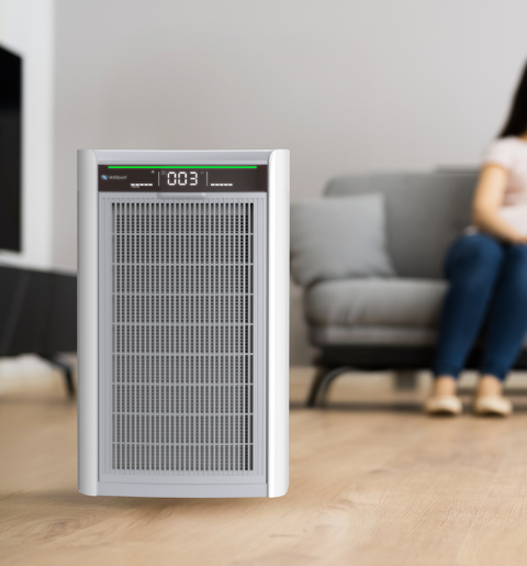Air purifier on a wooden floor with a blurred background of a living room.